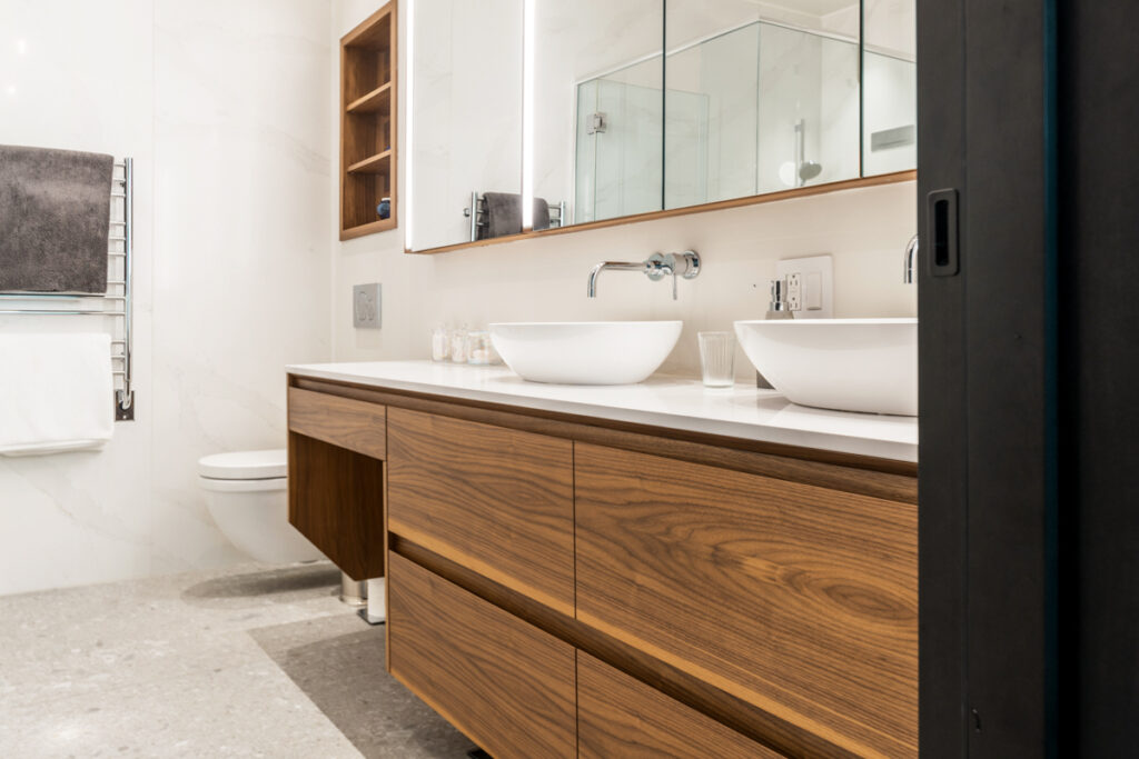 Photographie immobilière d’une salle de bain élégante avec double vasque, miroirs intégrés et matériaux raffinés, photo professionnelle réalisée au Québec.