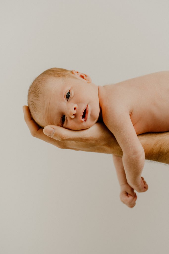 Nouveau-né photographié dans les bras d’un parent en séance lifestyle, image douce et intemporelle réalisée par une photographe spécialisée en photographie familiale au Québec.