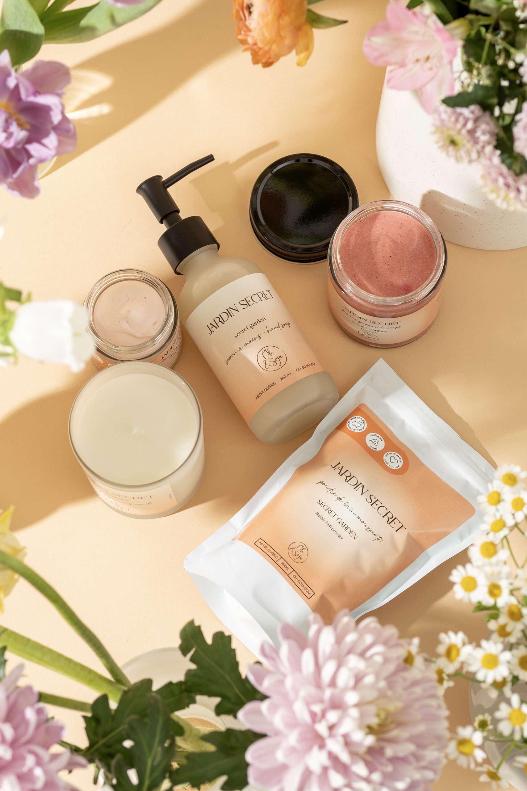 Produits de soins naturels présentés au centre de fleurs printanières sur fond beige – photographie commerciale lumineuse et florale