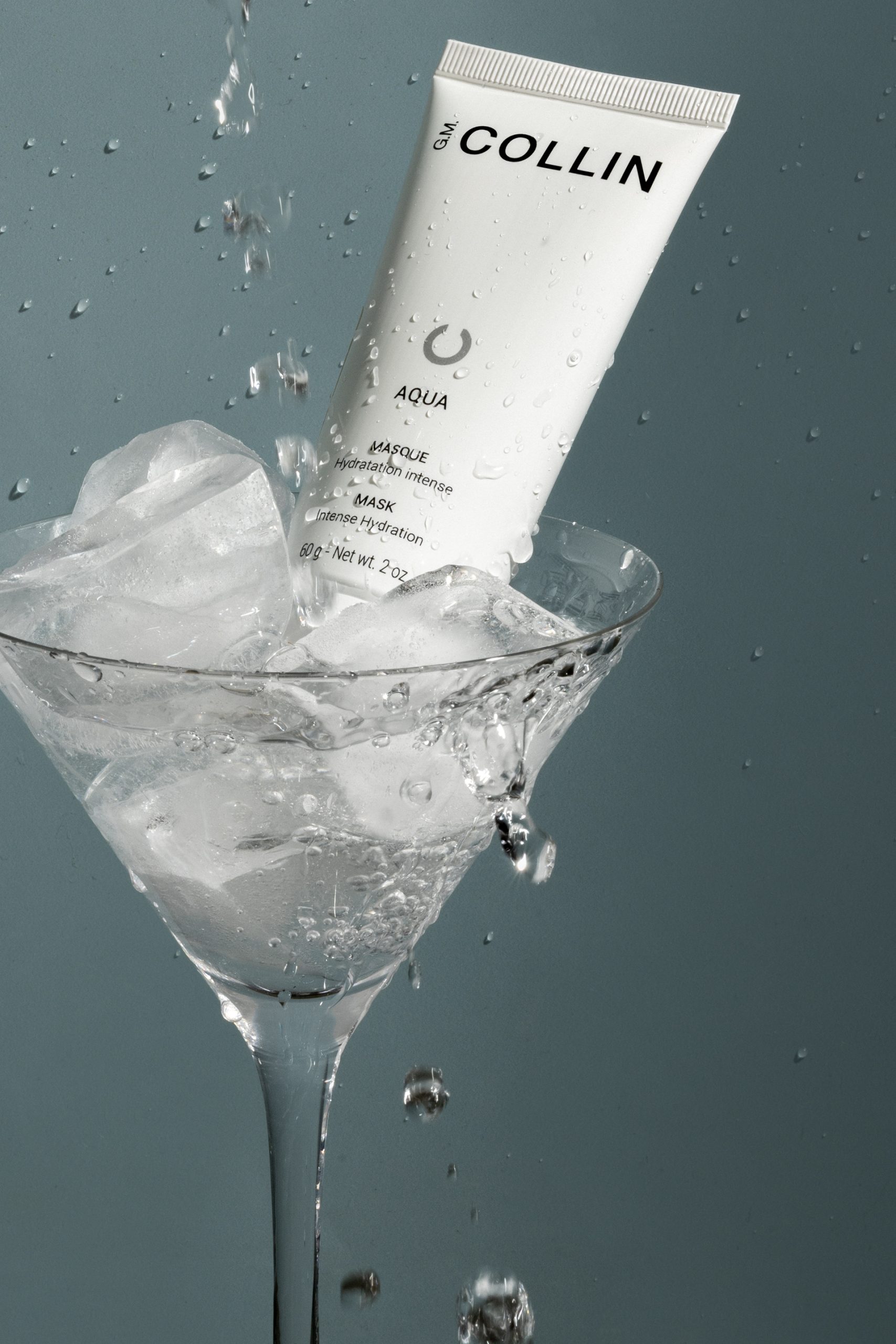 Photographie commerciale d’un soin G.M. Collin dans un verre à cocktail avec glace et éclaboussures – mise en scène créative et rafraîchissante
