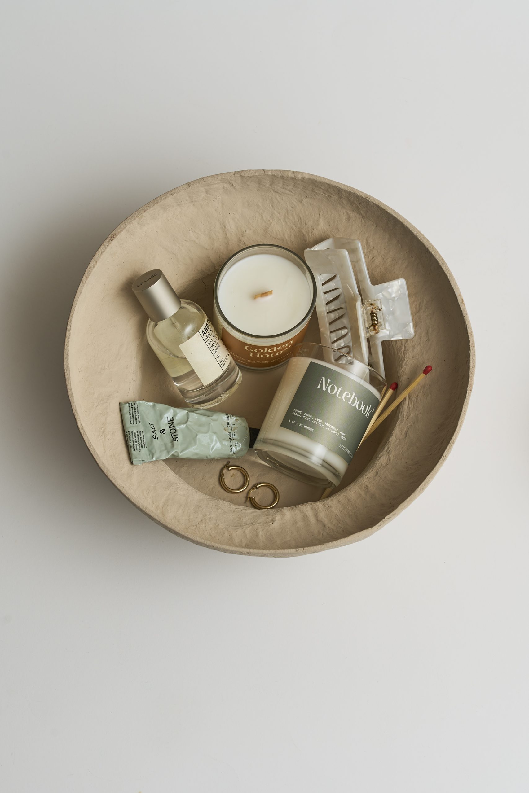 Photographie lifestyle de produits décoratifs et bien-être disposés dans un bol en terre cuite, ambiance chaleureuse et naturelle, création visuelle réalisée par une photographe commerciale au Québec.