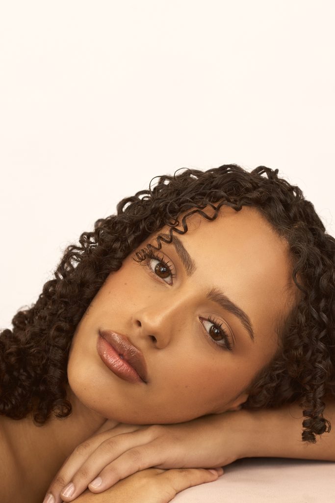 Photo professionnelle réalisée par une photographe commerciale capturant un portrait beauty lumineux avec peau glowy, regard doux et fond neutre; esthétique haut de gamme et minimaliste. (photographie beauté, branding, Montréal, Contrecœur)