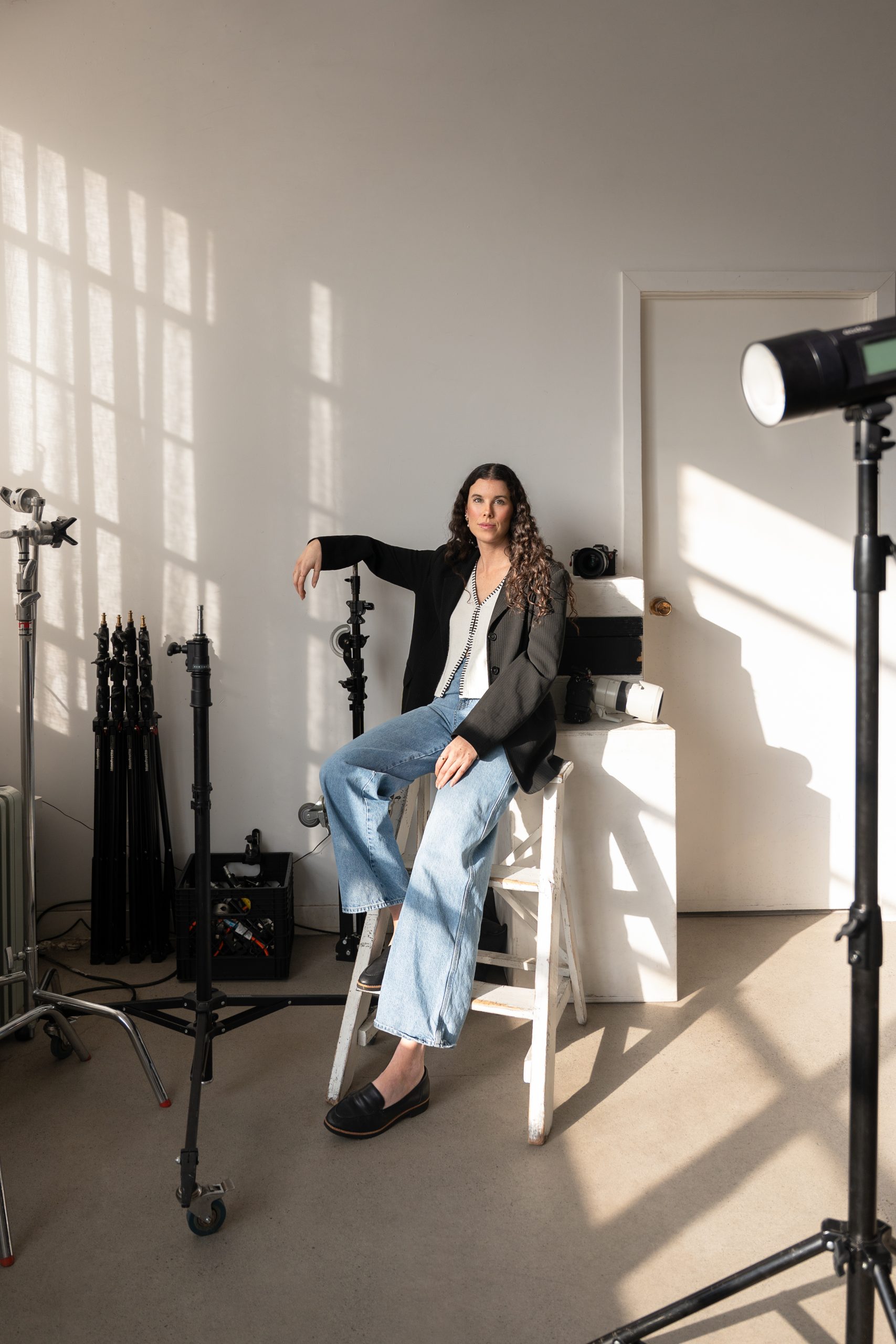 Photo professionnelle réalisée par une photographe commerciale capturant une scène de studio en lumière naturelle avec une femme assise, équipement de prise de vue et ambiance chaleureuse et créative. (photographe commerciale Québec, création de contenu, branding, Montréal)