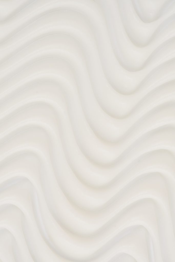 Fond texturé blanc aux formes ondulées et organiques créant une ambiance douce, épurée et moderne. Photographie de création de contenu idéale pour illustrer l’univers du bien-être, de la beauté et des soins personnels.