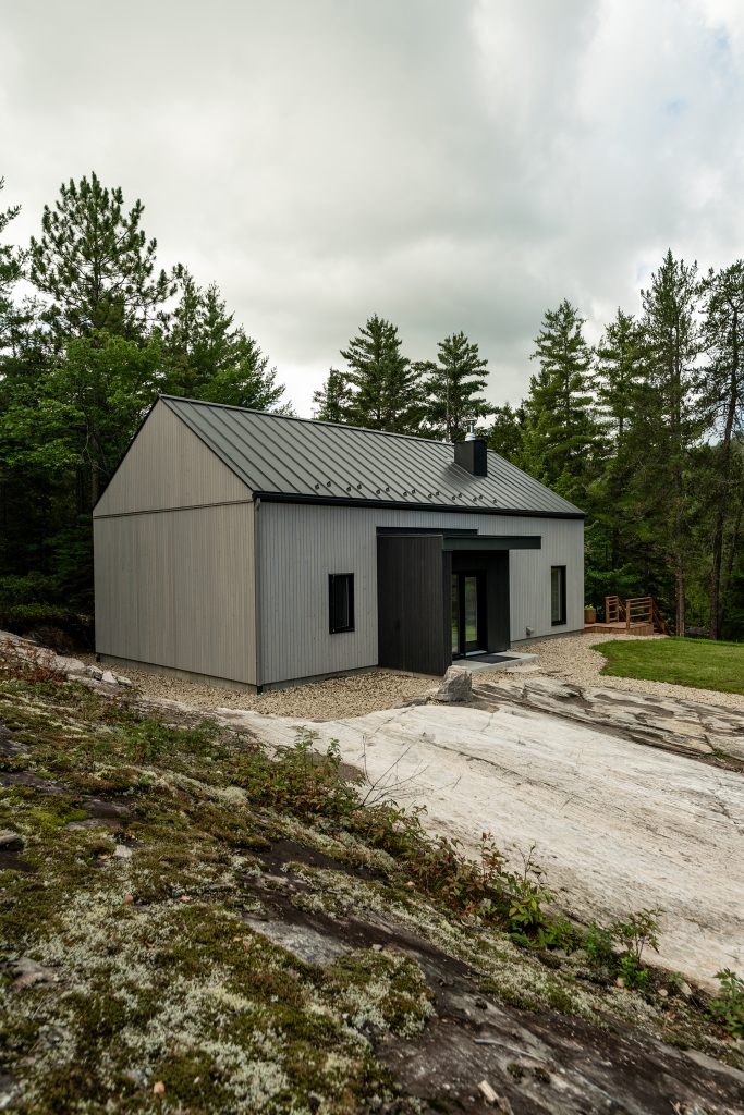 Photographie immobilière extérieure d’un chalet moderne entouré de forêt au Québec, réalisée par une photographe professionnelle.