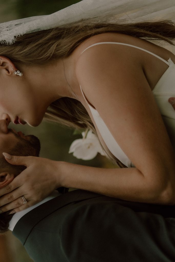 Portrait intime de jeunes mariés s’embrassant sous le voile de la mariée, photographie de mariage naturelle et éditoriale au Québec.