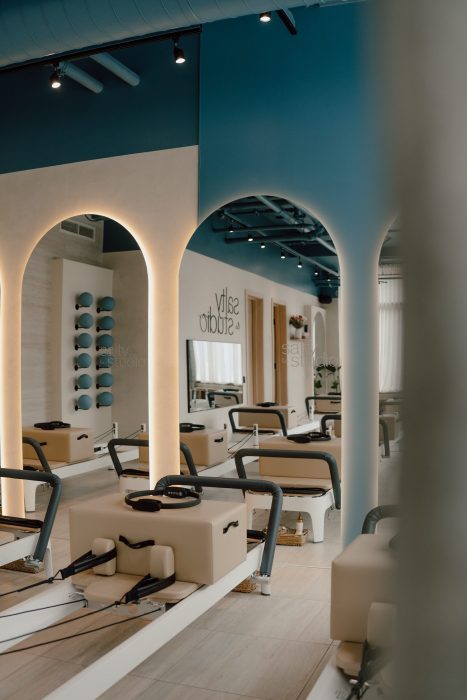 Photo professionnelle réalisée par une photographe commerciale présentant l’intérieur d’un studio pilates au design épuré, arches lumineuses et équipements beige. (photographe commerciale Québec, branding, architecture intérieure, Montréal)