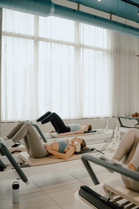 Photo professionnelle réalisée par une photographe commerciale capturant un cours de pilates en groupe dans un studio lumineux à lumière douce, ambiance beige et bleu pastel. (photographe commerciale Québec, contenu branding, studio pilates, Montréal)