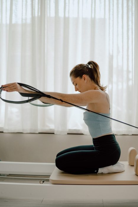 Photo professionnelle réalisée par une photographe commerciale capturant un exercice de pilates en studio lumineux, esthétique minimaliste et bien-être. (photographe commerciale Québec, contenu commercial, studio pilates Montréal)