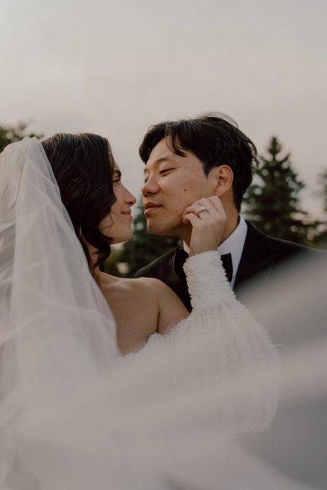 Portrait intime des mariés se regardant avec tendresse en lumière naturelle, la mariée portant un voile et le marié en costume, photo de mariage naturelle captée par une photographe de mariage au Québec.