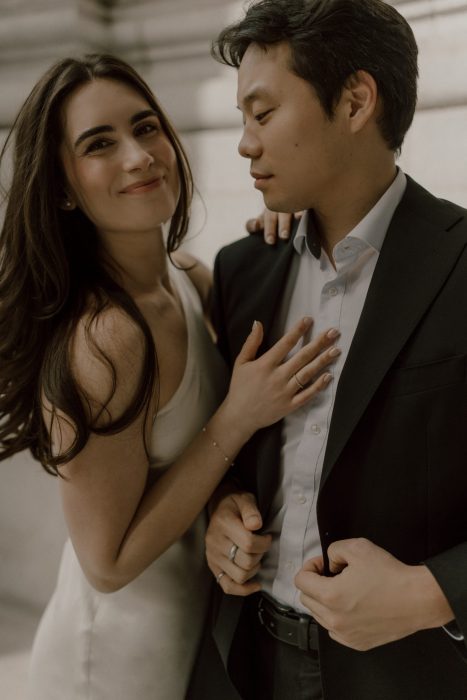Portrait rapproché d’un couple complice pendant leur séance fiançailles, la future mariée souriant à la caméra tandis que son partenaire la regarde tendrement.